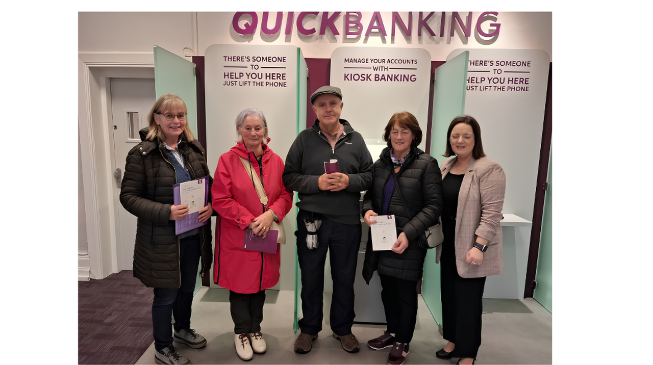 Five people standing in a bank lobby under a 